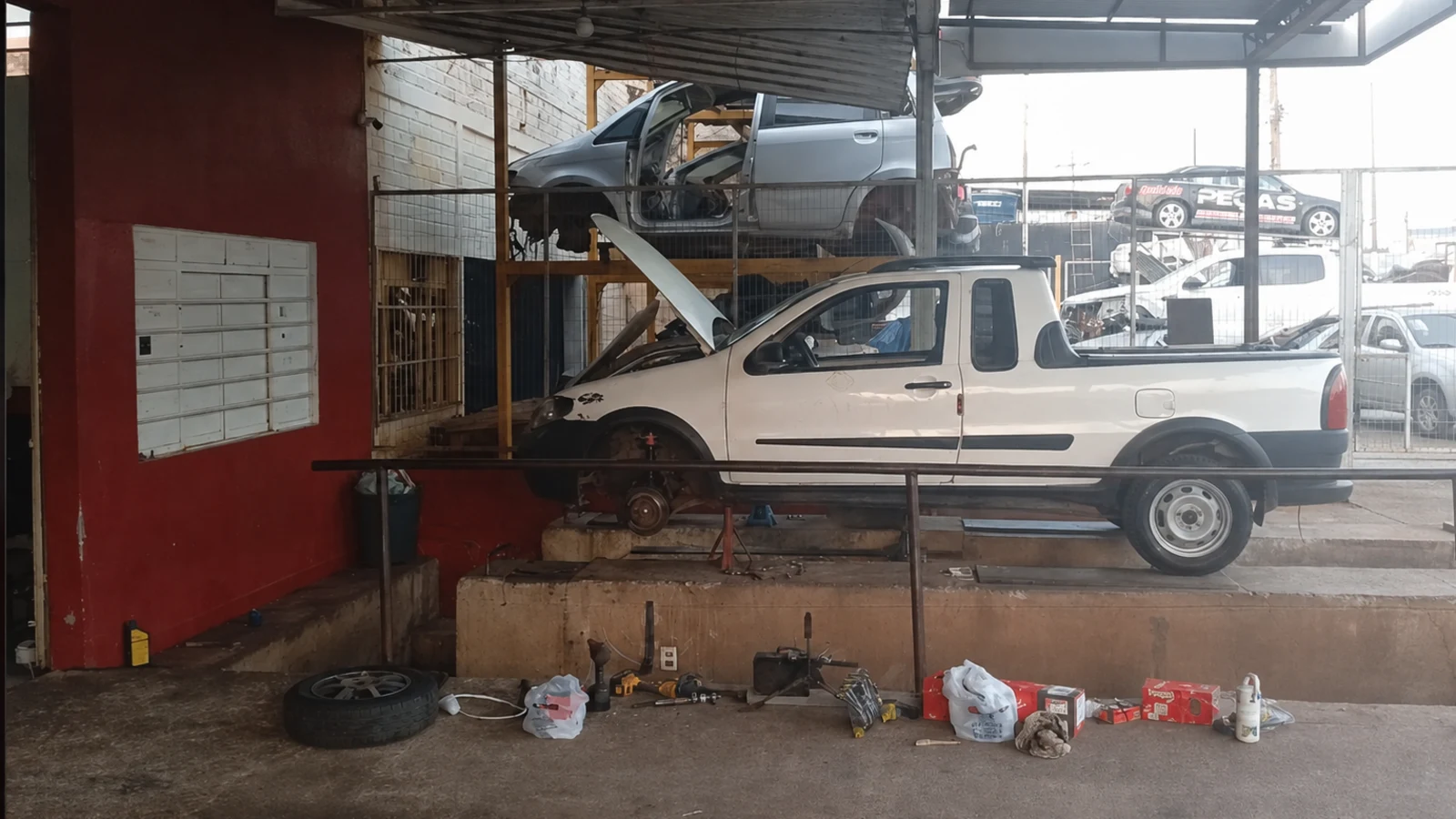 Pickup com o capô aberto sobre a rampa do box coberto da Dolla Auto Center.